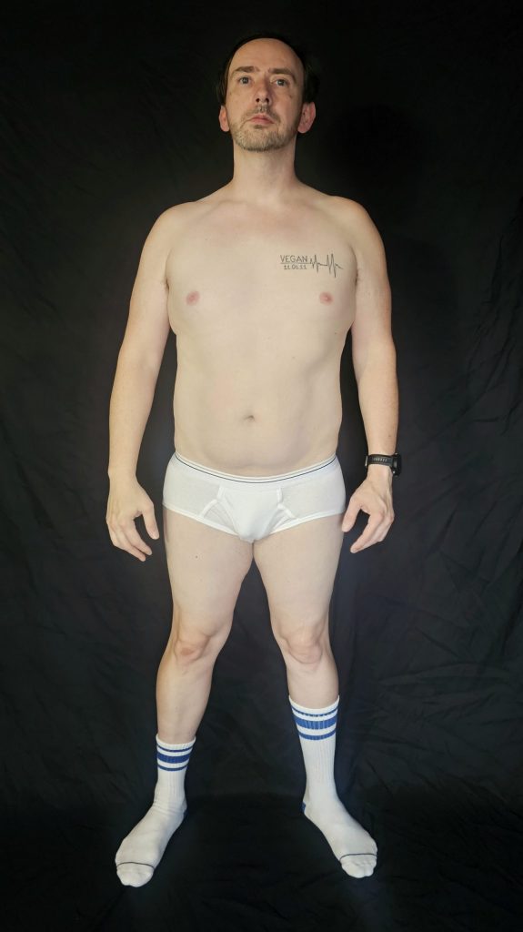 Front progress photo of Joshua Marron in white briefs and blue-striped socks, showing physique at the end of Week 1 of Project Legacy transformation.