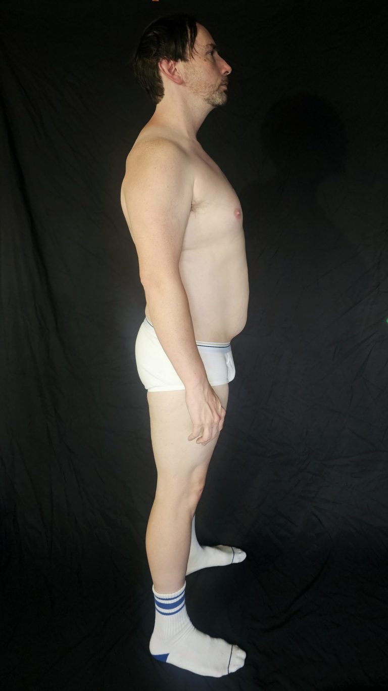 Side profile of Joshua Marron in briefs and socks showing abdominal shape and posture at the end of Week 1 in Project Legacy.