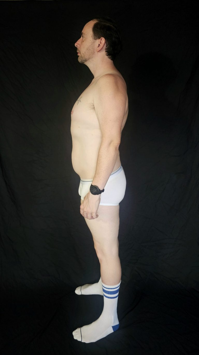 Left profile of Joshua Marron showing physique progress at end of Week 1 in Project Legacy, wearing white briefs and striped socks.