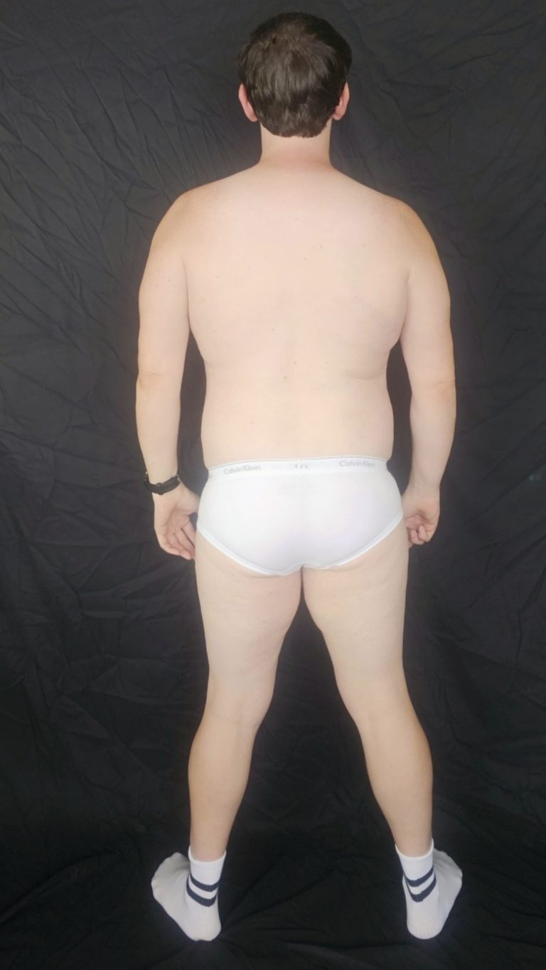Joshua Marron standing with back facing camera in white briefs and socks, relaxed pose for Project Legacy vegan fitness progress.
