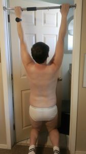 Joshua Marron hanging from pull-up bar facing away in white briefs and socks for Project Legacy vegan transformation photo.