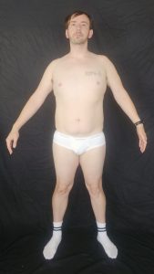 Joshua Marron facing forward with arms extended outward in white briefs and socks for Project Legacy fitness progress photo.