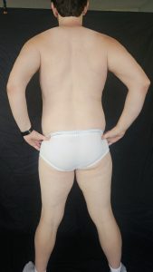 Joshua Marron facing backward, hands on hips in white briefs and socks for Project Legacy vegan body transformation progress photo.
