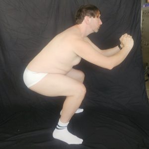 Joshua Marron in side squat pose wearing white briefs and socks for Project Legacy fitness progress tracking.