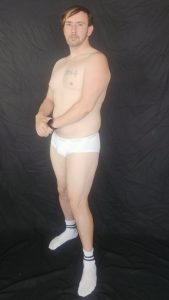 Joshua Marron turned left performing vacuum pose in white briefs and socks for Project Legacy core muscle progress photo.