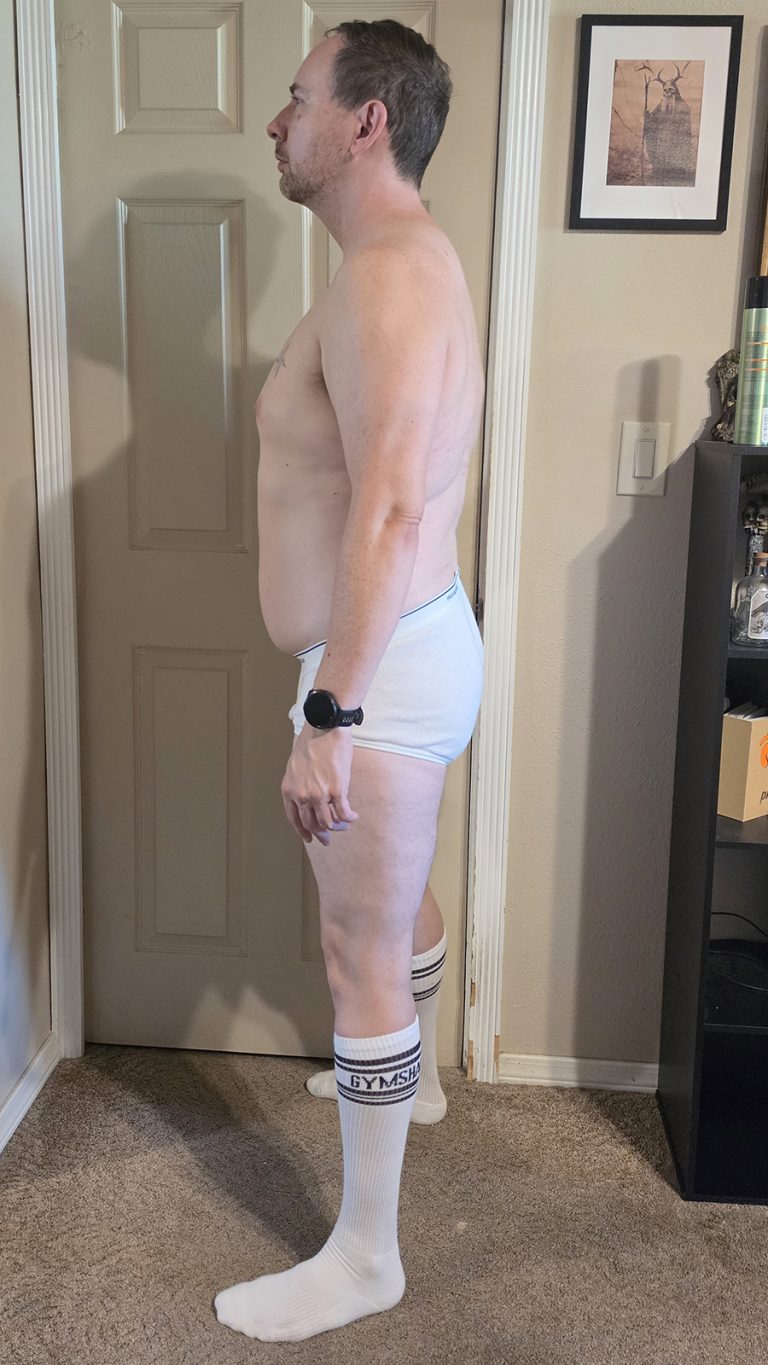 Week 2 progress photo of Joshua Marron in white briefs and socks, standing in a Left Side pose for the Resurgam transformation.